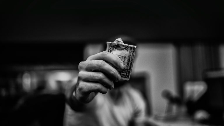 Person holding cash in front of their face. Black and white photo.