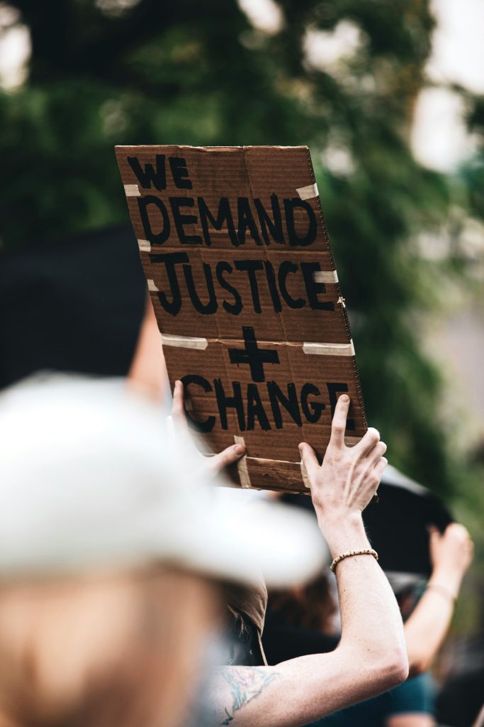 A person holding a sign that says we demand justice and change