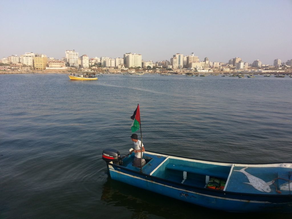 Person on boat holding Palestinian flag