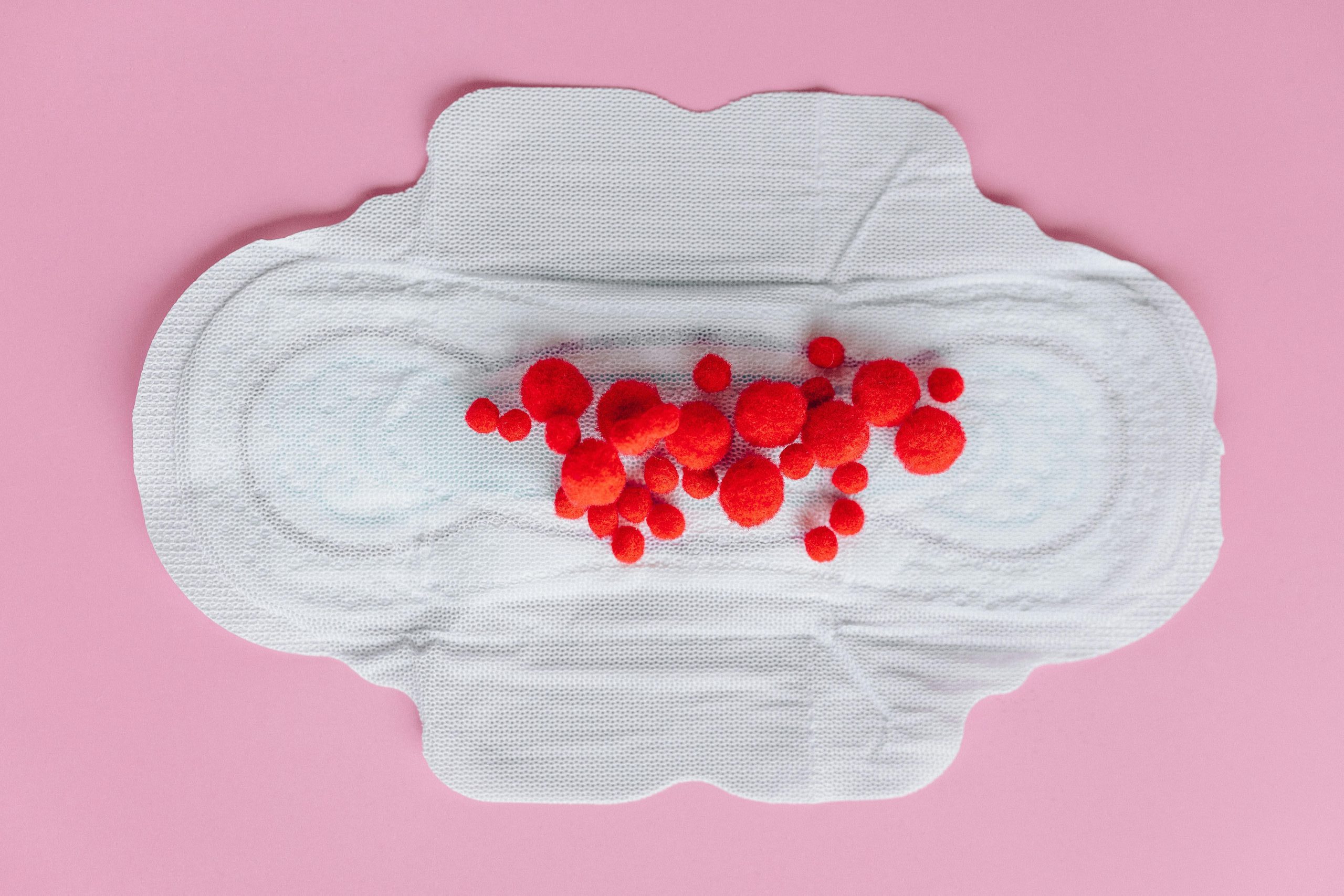 Top view of a sanitary pad with red raspberries. menstrual health international women's day 2025