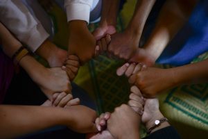 many people holding hands in a circle.